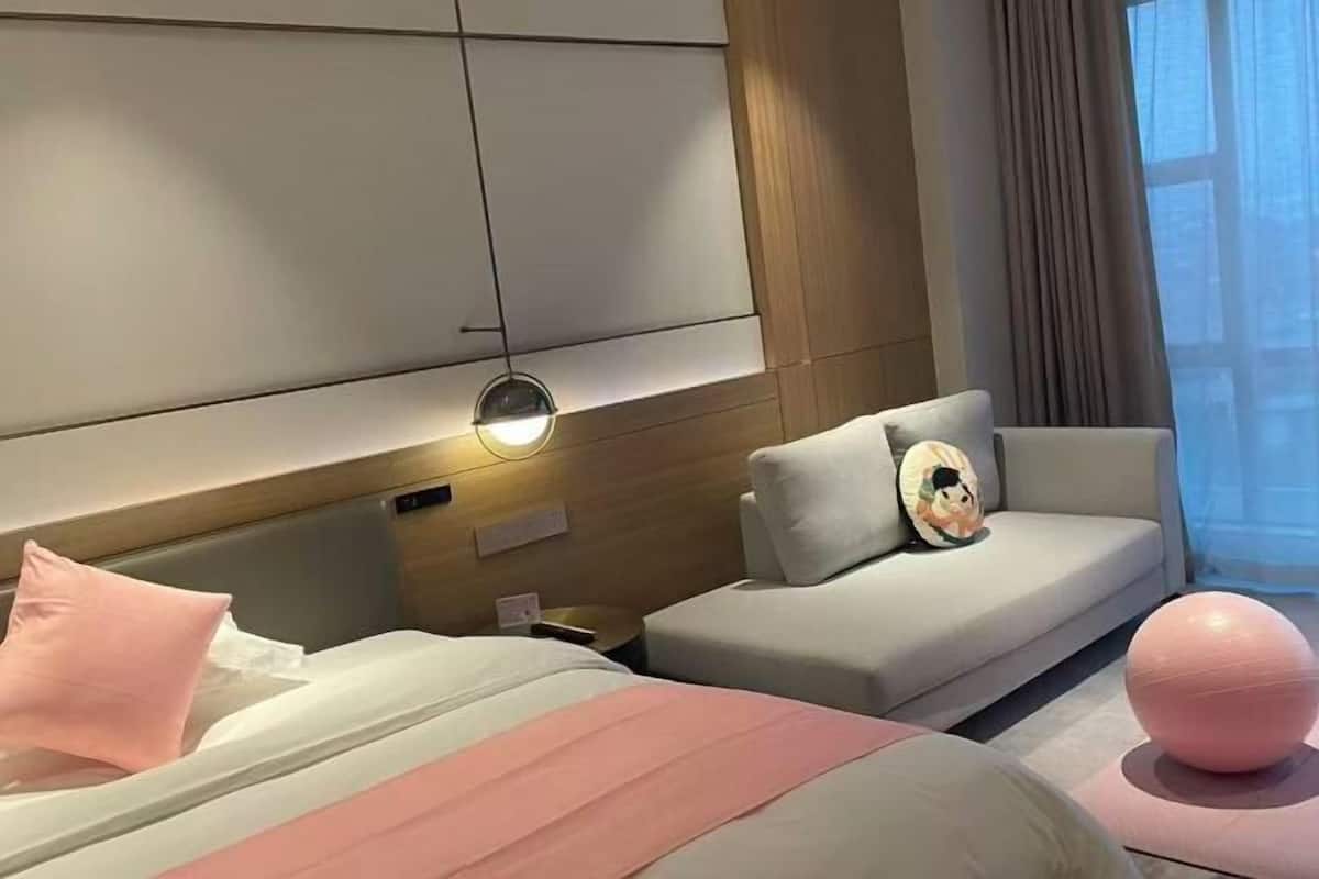 A modern hotel room with a bed, a sofa, and a workout ball.