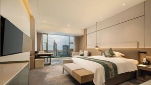 Ein modernes Hotelzimmer mit einem großen Bett, einem Schreibtisch und Blick auf die Stadtlandschaft.
