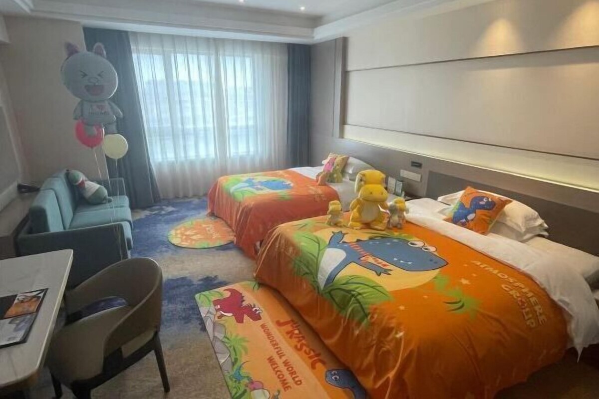 A hotel room with two beds, a sofa, a table, and a chair.