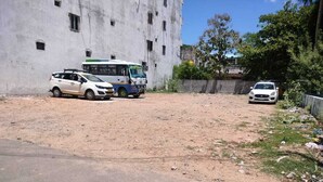 A parking area with a white car, a bus, and a building in the background. - TCS Residency (Kanchipuram)
