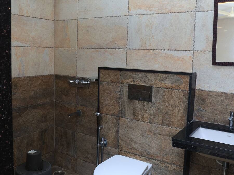A bathroom with a shower, toilet, sink, and trash bin.