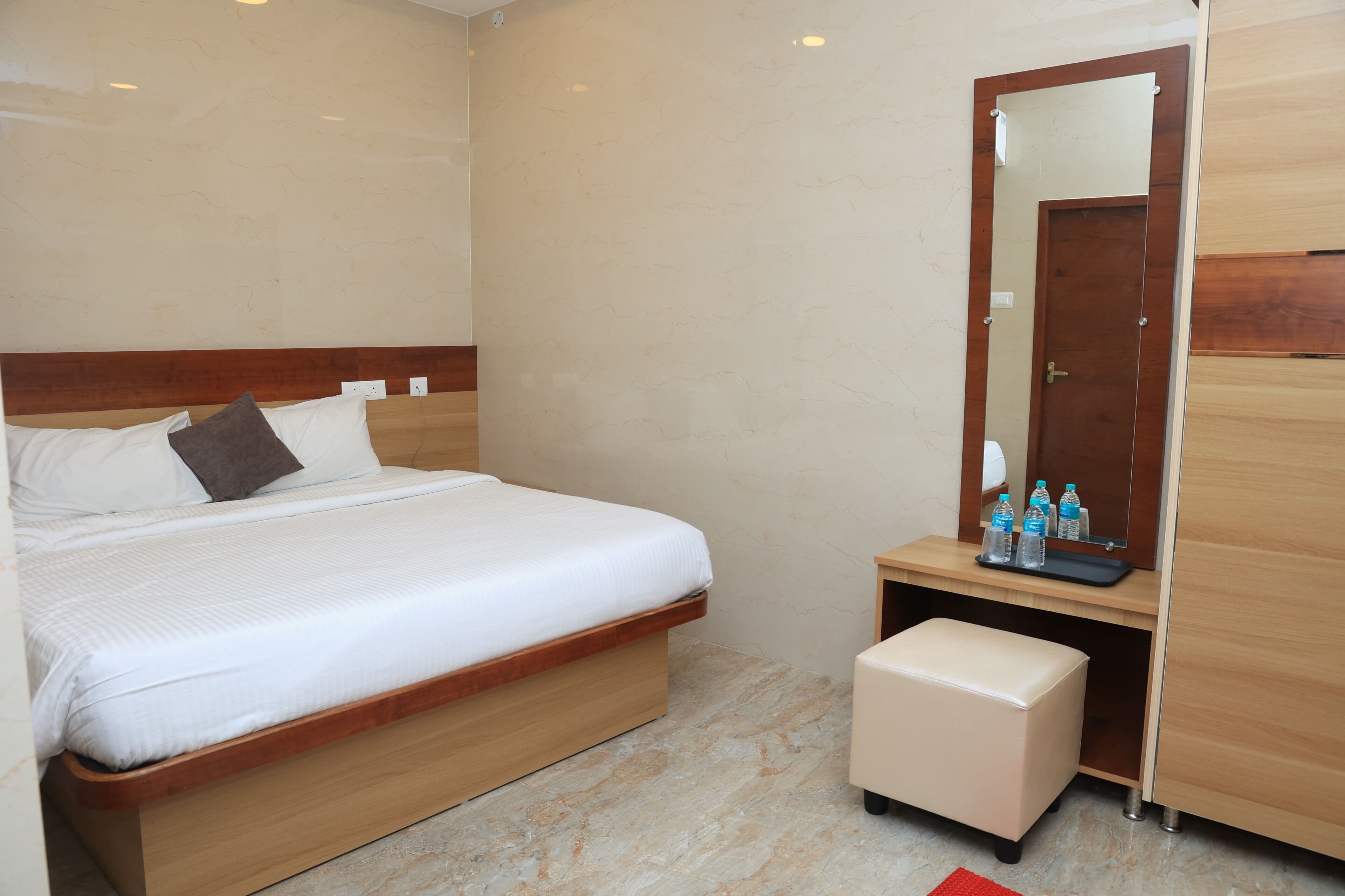 A bedroom with a bed, a wooden nightstand, a mirror, and a wardrobe.