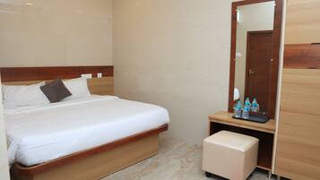 A bedroom with a bed, a wooden nightstand, a mirror, and a wardrobe.
