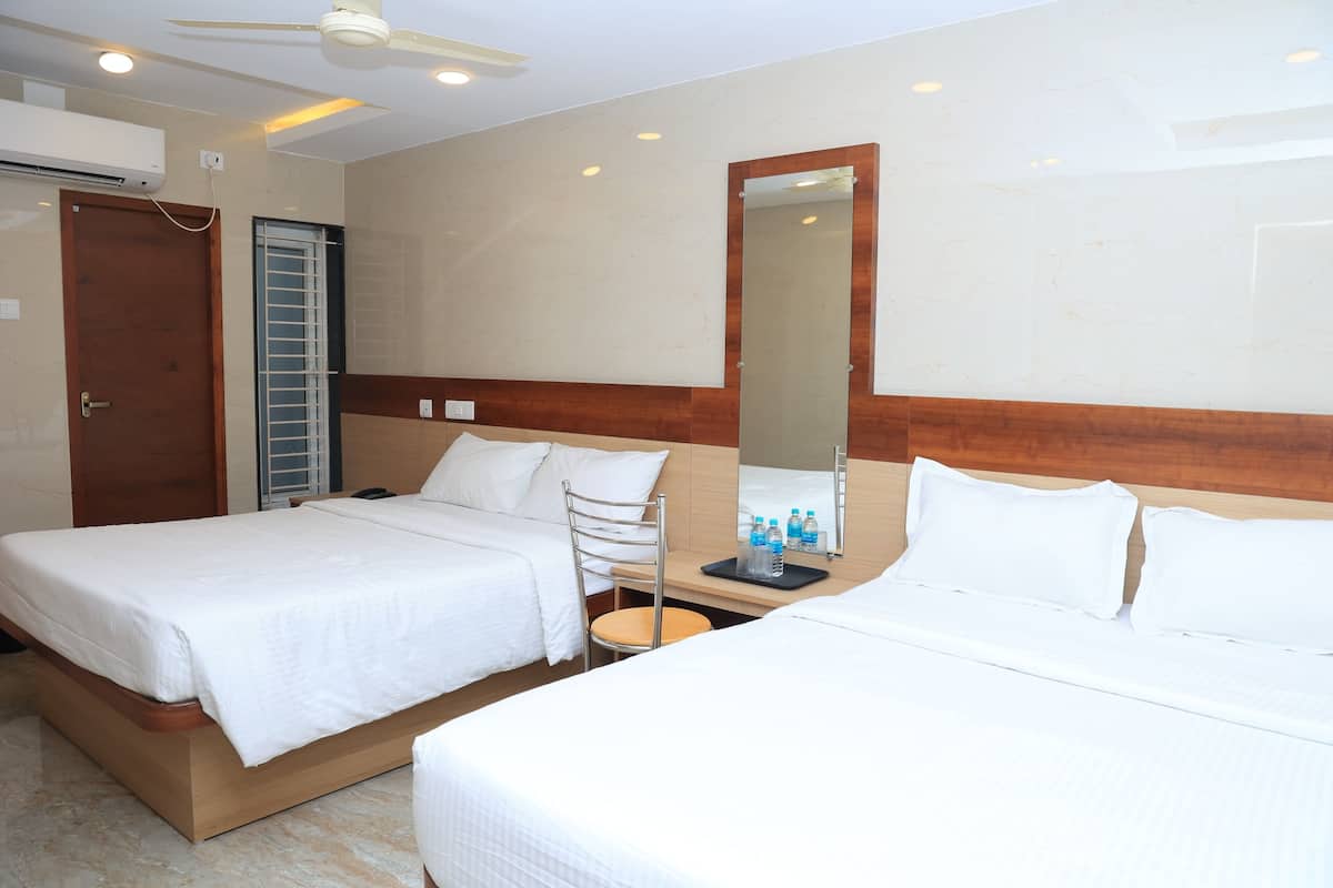 Une chambre d’hôtel avec deux lits, une tête de lit en bois, un miroir, un bureau avec une chaise et un ventilateur de plafond.
