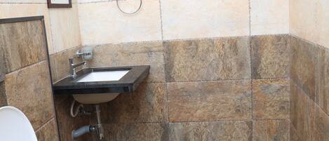 A small bathroom with a toilet, sink, and shower area.