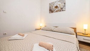 Una habitación de hotel con una cama, dos mesitas de noche, una lámpara de pared y un cuadro.