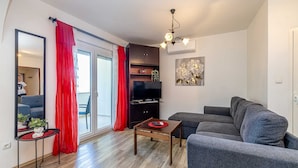Una sala de estar moderna con un sofá gris, una mesa de centro de madera y un televisor de pantalla plana.