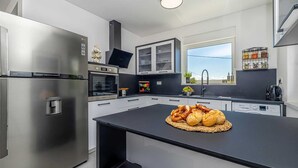 A modern kitchen with stainless steel appliances, a central island with food, and a window with a city view. - Villa KATHARINA with private pool (Žgaljići)
