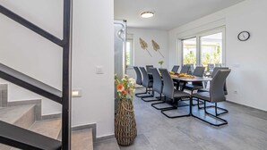 A modern dining area with a long table, chairs, and a vase of flowers. - Villa KATHARINA with private pool (Žgaljići)