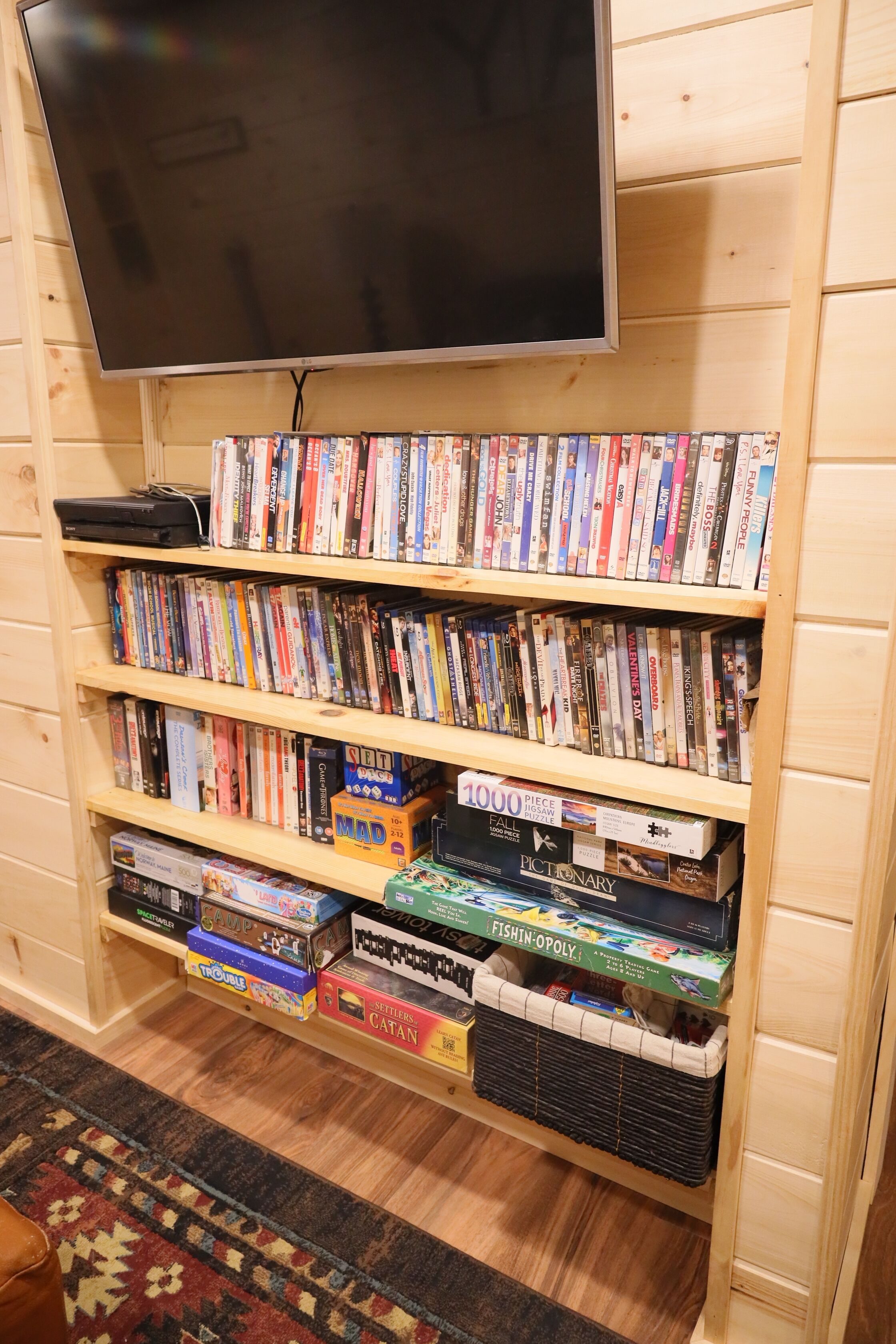 A bookshelf with various board games and a television above it.