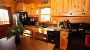 A wooden cabin-style kitchen with a refrigerator, stove, sink, and wooden cabinets. - Cozy Log Cabin, Sleeps 6, Pet Friendly! (Norway)