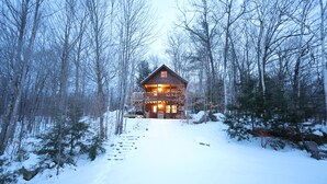 A log cabin with a balcony, surrounded by snow-covered trees. - Cozy Log Cabin, Sleeps 6, Pet Friendly! (Norway)