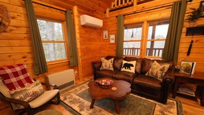 A cozy cabin interior with a leather sofa, a rocking chair, a coffee table, and a fireplace. - Cozy Log Cabin, Sleeps 6, Pet Friendly! (Norway)