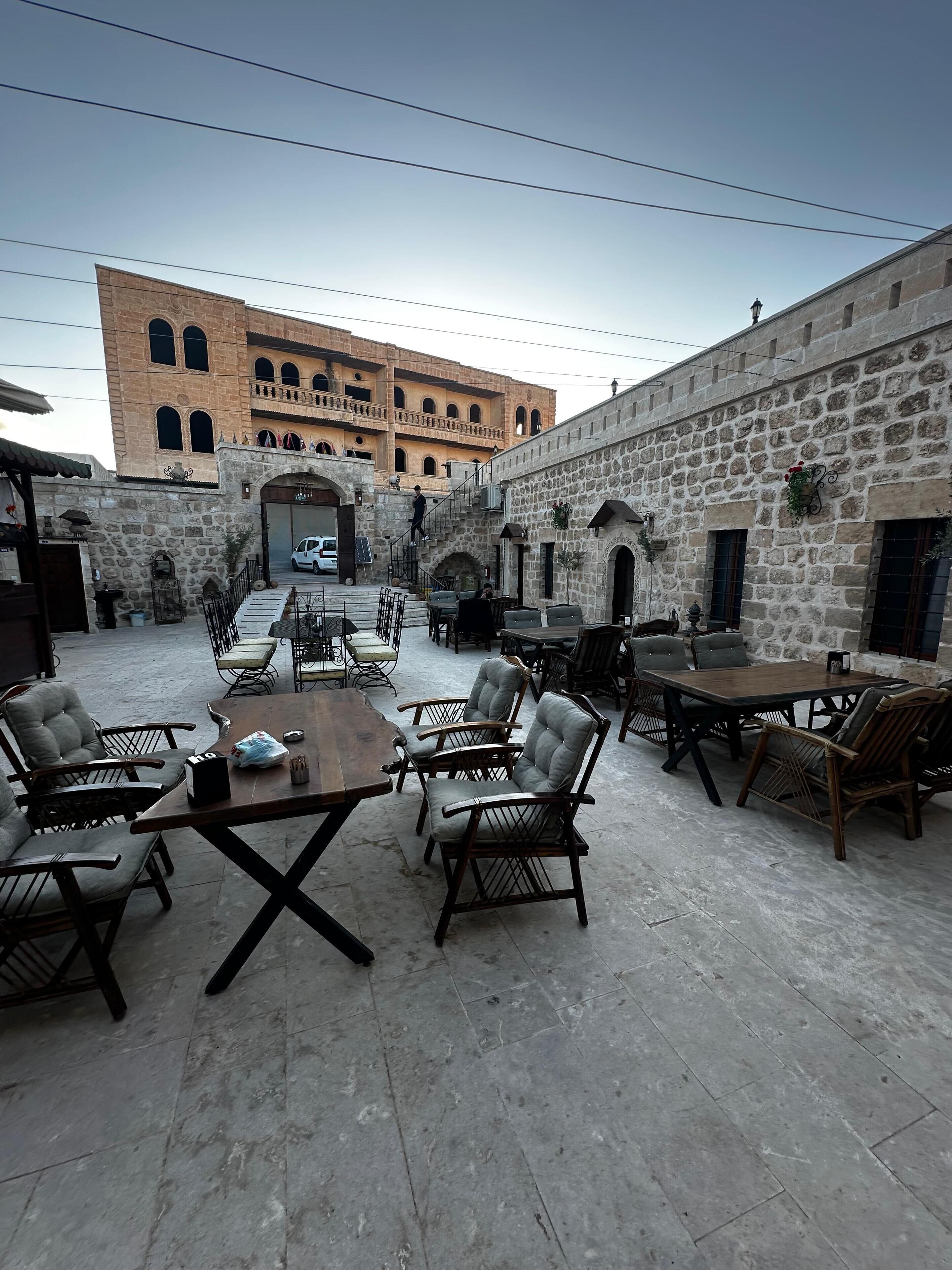 An outdoor seating area with stone walls and tables, surrounded by stone buildings.