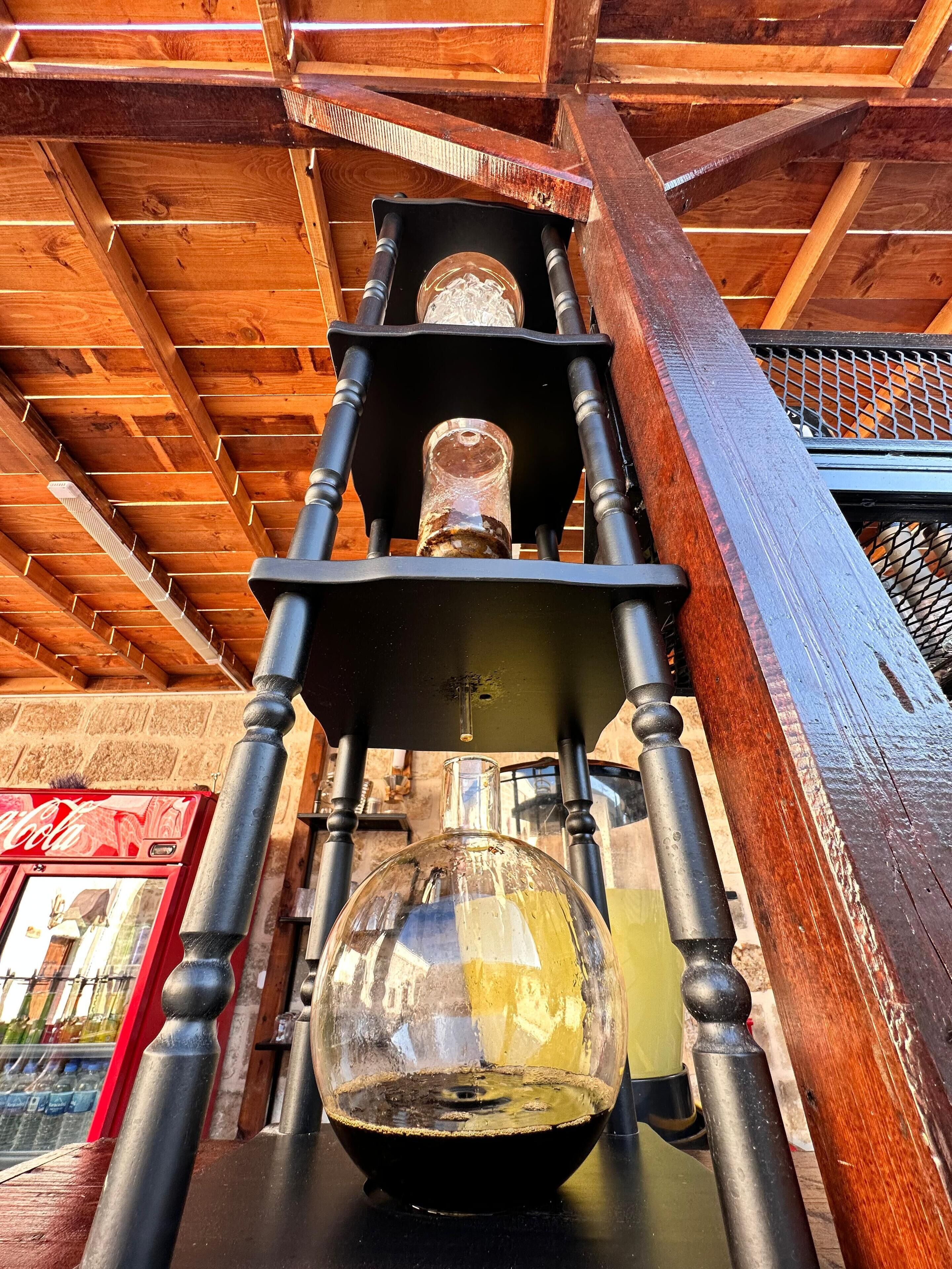 A wooden structure with a glass enclosure, possibly a distillation apparatus, under a wooden roof.