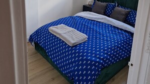 A bedroom with a bed, a nightstand, a lamp, and a window. - A lovel one bedroom.  (London)