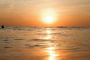 A sunset over a calm sea with a silhouette of a person in the distance. - Casas Alba (Cóbano)