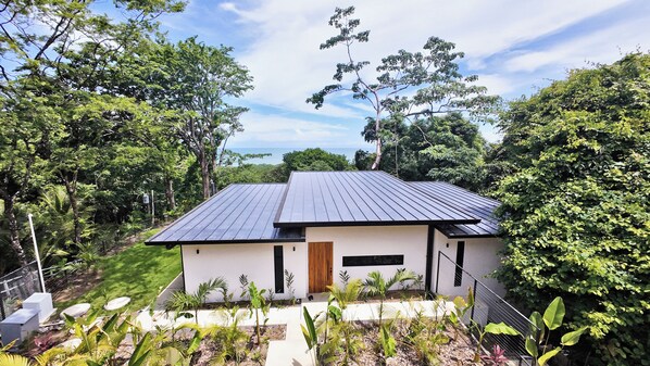A modern house with a flat roof, surrounded by lush greenery and trees. - Casas Alba (Cóbano)