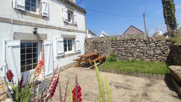 A white building with multiple windows and a stone wall. - Maison Bretonne à la Pointe du Raz (Plogoff)