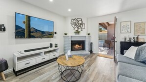 Ein Wohnzimmer mit Flachbildfernseher, Kamin, Sofa und Couchtisch.