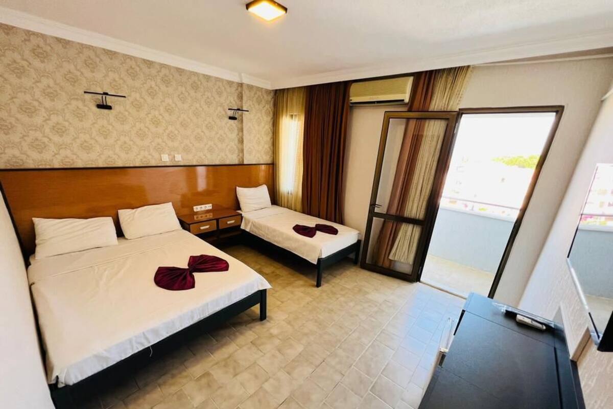 A hotel room with two beds, a desk, and a large window.