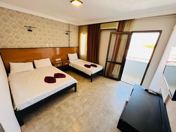 A hotel room with two beds, a desk, and a large window. - Blue Golden Sea (Kusadasi)
