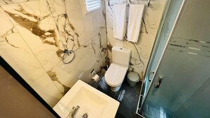 A bathroom with a marble floor, a sink, a toilet, and a glass shower enclosure. - Blue Golden Sea (Kusadasi)