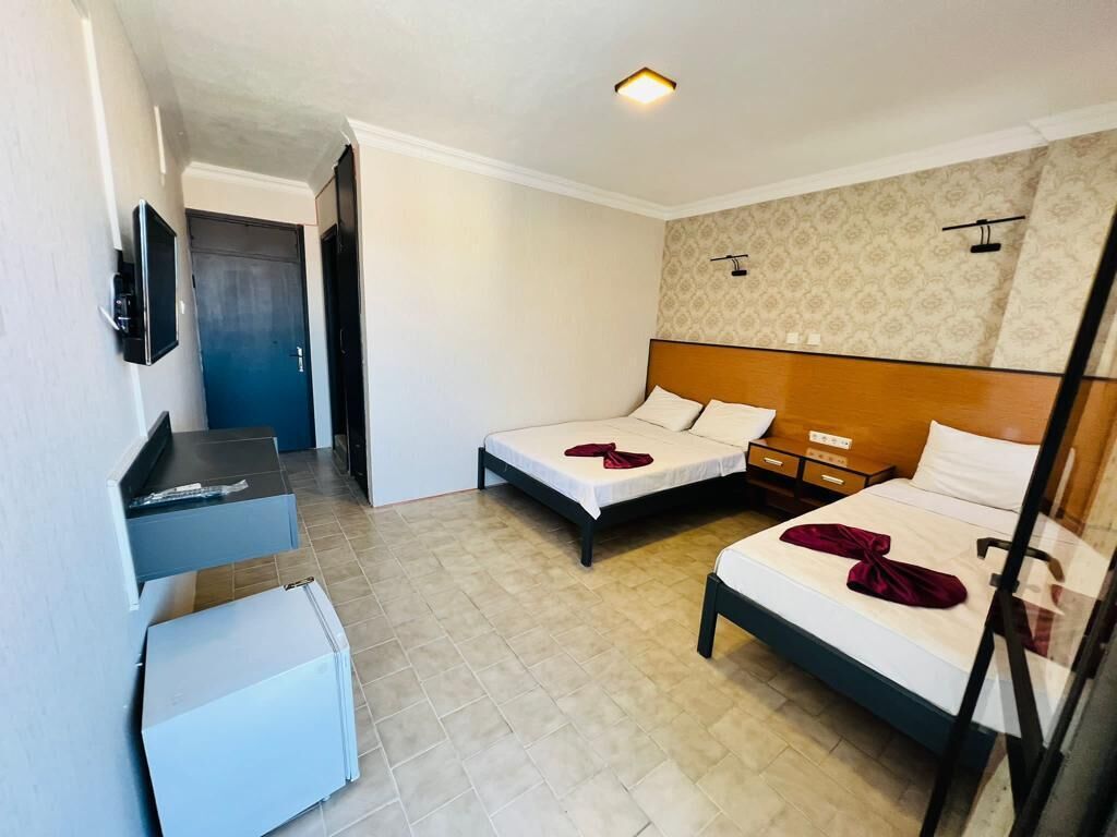 Et hotelværelse med to senge, et skrivebord og et fjernsyn.