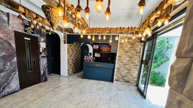 A hotel reception area with a marble floor, a reception desk, and a reception sign. - Blue Golden Sea (Kusadasi)