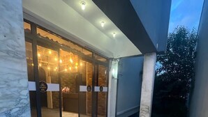 A modern outdoor patio area with a glass door entrance, a tiled floor, and a ceiling with recessed lighting. - Blue Golden Sea (Kusadasi)