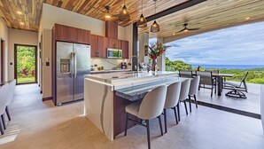 A modern kitchen with a large island, stainless steel appliances, and a view of the outdoors.
