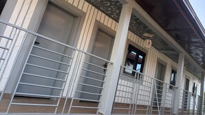 Un edificio con porche cubierto, barandillas de metal y varias ventanas.