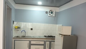 Una cocina compacta con un lavamanos, armarios, una estufa y un refrigerador.