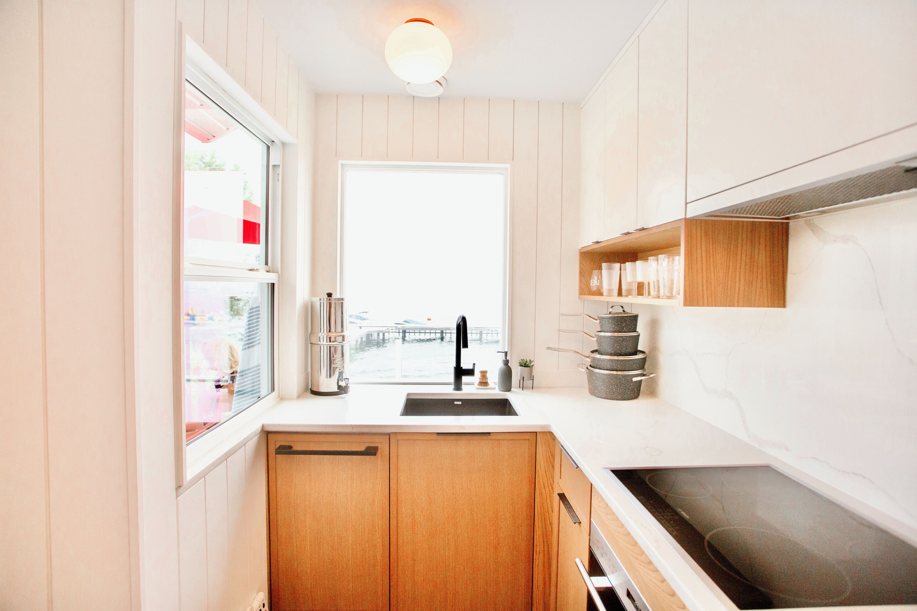 A modern kitchen with wooden cabinets, a white countertop, a black faucet, and a window with a view of a bridge.