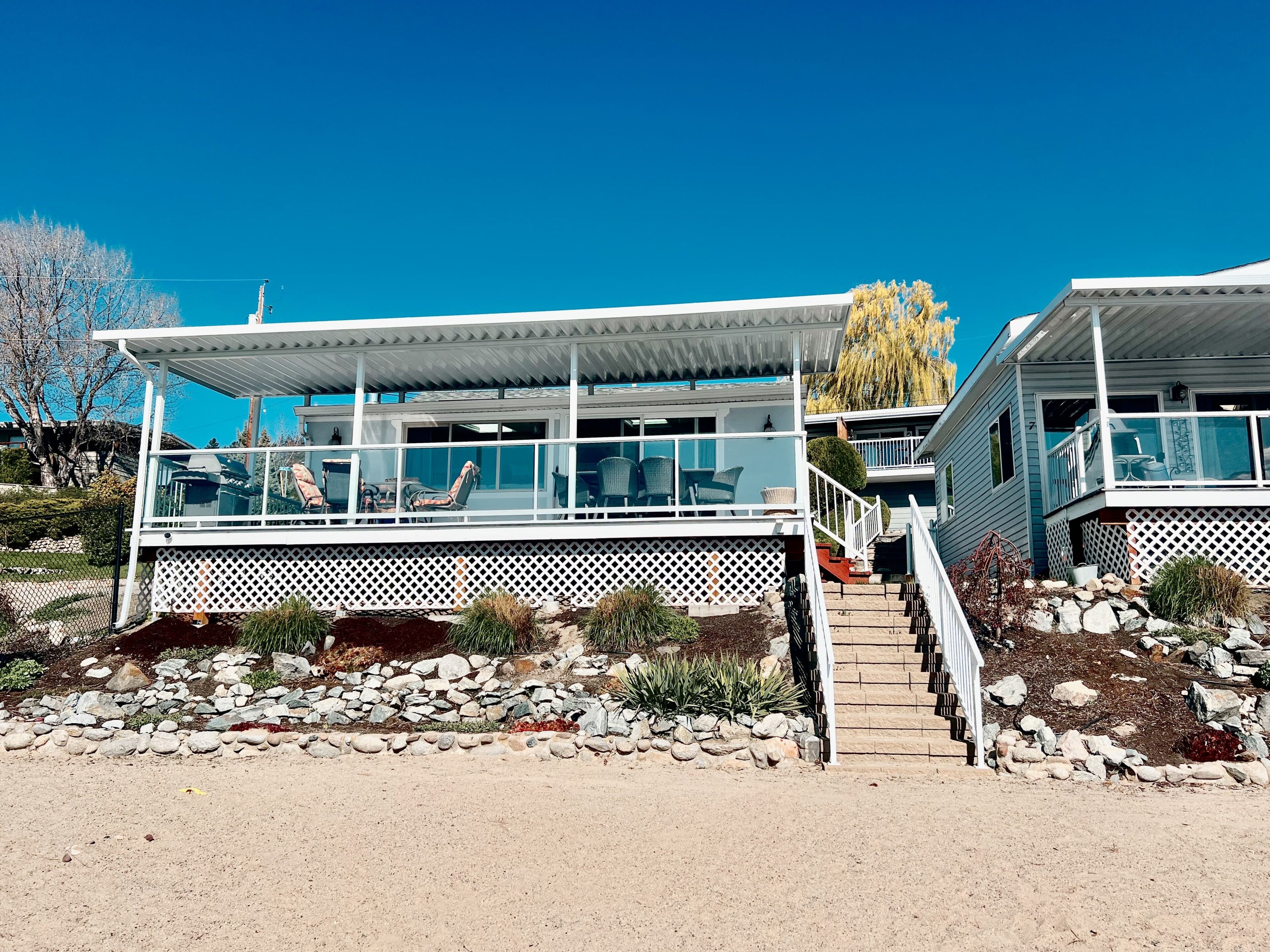 Une maison moderne à deux étages dotée d’un patio couvert aménagé avec du mobilier d’extérieur.