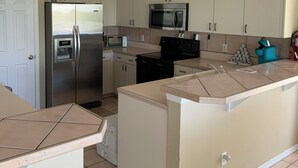 Une cuisine avec des meubles blancs, un réfrigérateur en acier inoxydable, un four à micro-ondes et un grille-pain.