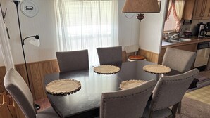 A dining area with a dark wooden table, six upholstered chairs, and woven placemats. - Country fishing paradise (Moore Haven)