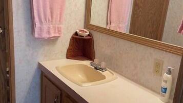 A bathroom with a sink, mirror, wooden cabinets, and a pink towel hanging on a towel rack.