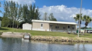 A single-story mobile home with a small water feature in front. - Country fishing paradise (Moore Haven)