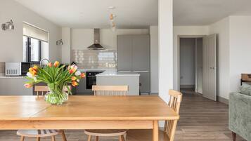 A modern kitchen with a central island, wooden dining table, and chairs.