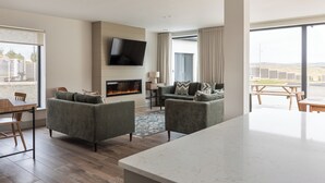 Un salon moderne doté d’une cheminée, d’un téléviseur à écran plat fixé au mur et d’une grande fenêtre donnant sur l’extérieur.
