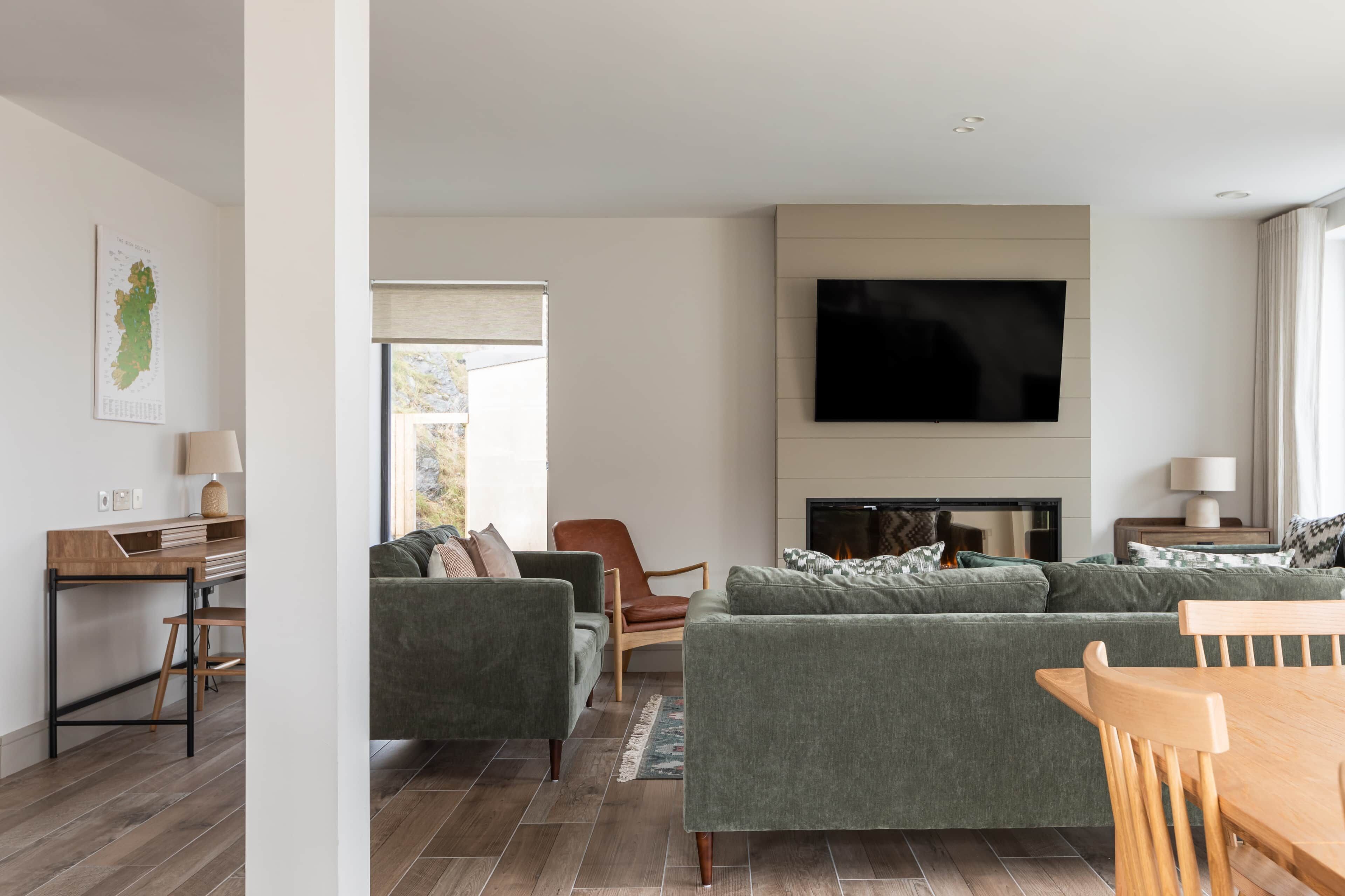 A modern living room with a sofa set, a flat-screen TV, and a fireplace.