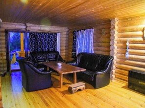 Cozy cabin interior with a dark leather sofa set and wooden coffee table.