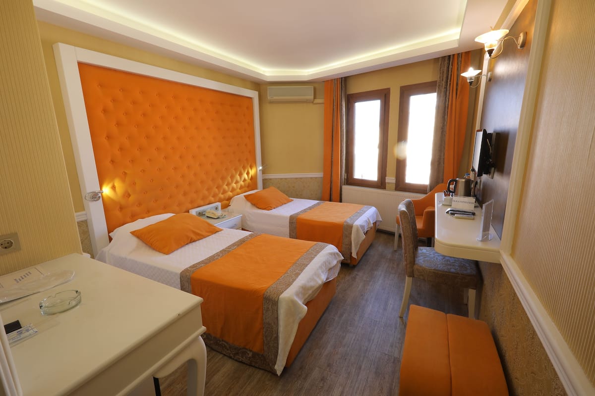 Une chambre d’hôtel avec deux lits, un bureau, une chaise et un téléviseur.