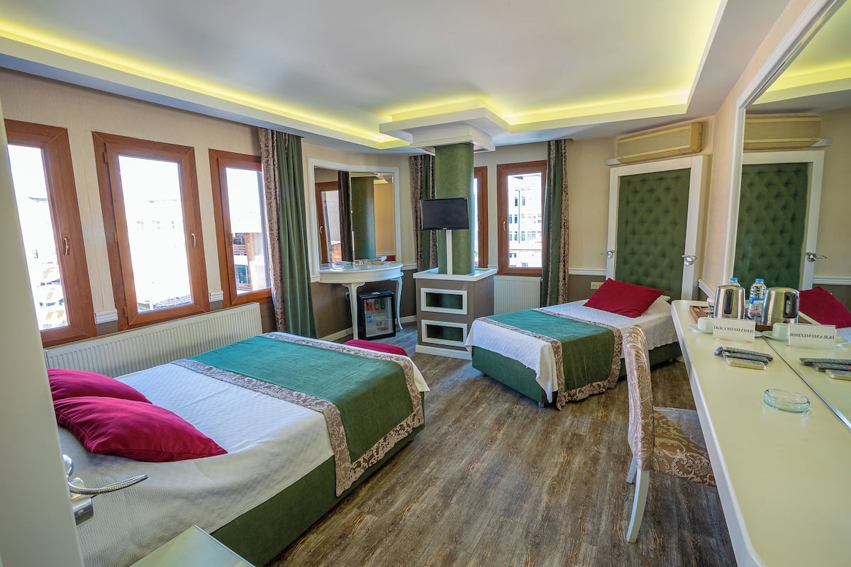 Une chambre d’hôtel avec deux lits, un bureau, un miroir et une télévision.