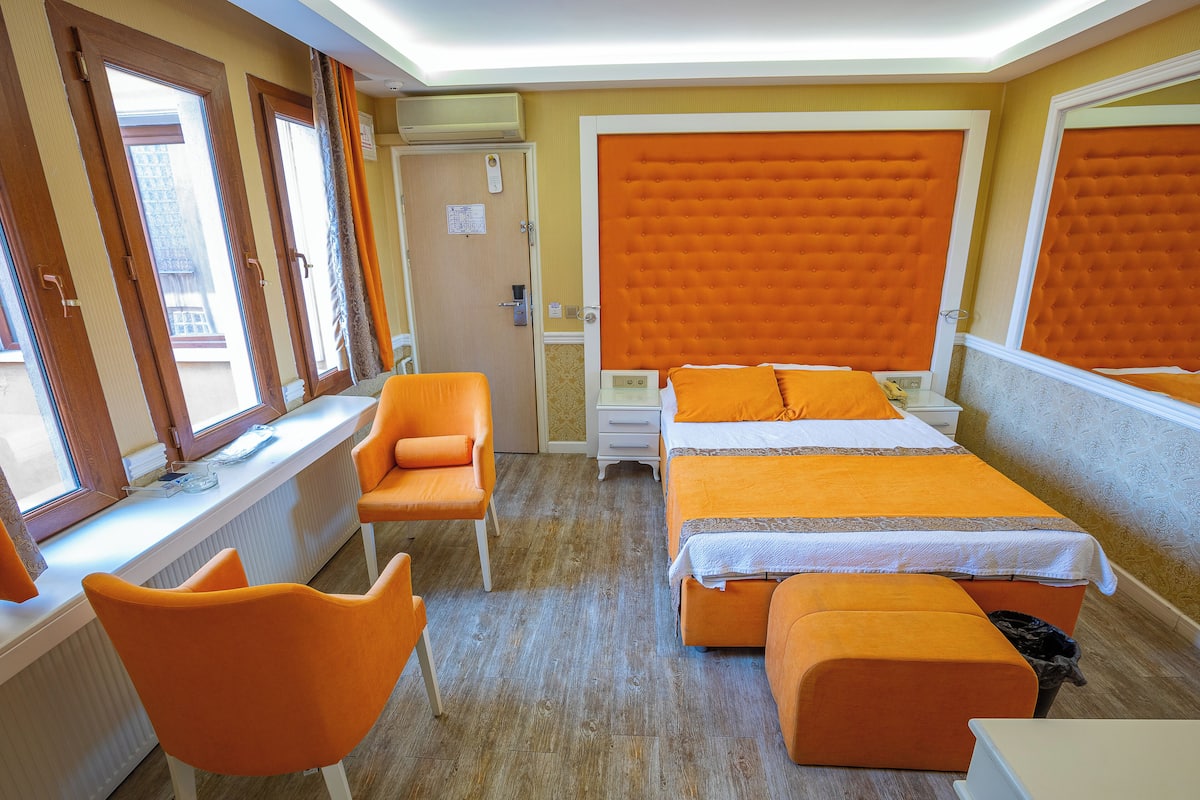 Une chambre d’hôtel avec deux lits, une fenêtre avec des rideaux, un bureau et une chaise.