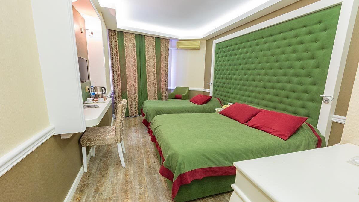 A hotel room with two beds, a desk, and a chair.