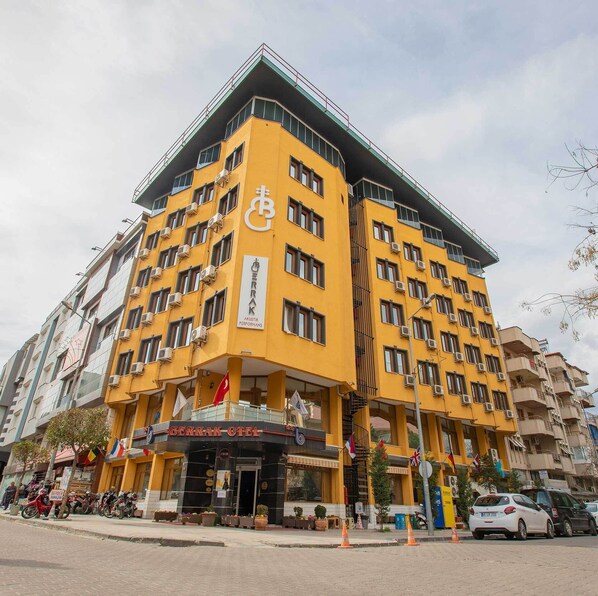 A multi-story hotel with a yellow facade, balconies, and a sign indicating it is a hotel. - Berrak Otel (Salihli)