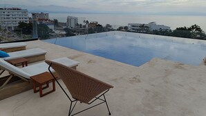 An infinity pool with lounge chairs and a view of the sea.
