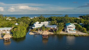 Une propriété située sur la côte, comprenant plusieurs bâtiments, un quai et une structure dotée d’un toit de chaume.